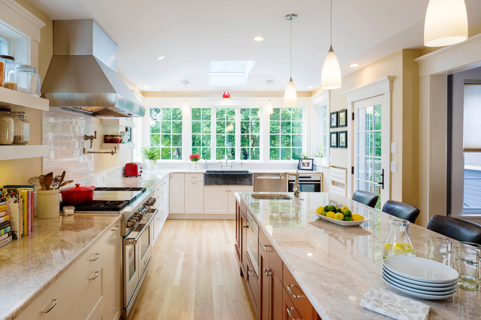 Design ideas for a large transitional l-shaped kitchen in Boston with recessed-panel cabinets, white cabinets, quartz benchtops, white splashback, subway tile splashback, stainless steel appliances, light hardwood floors and with island.