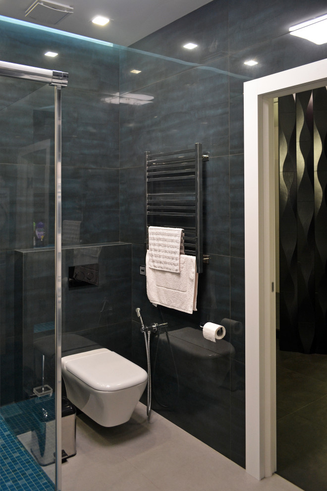 Идея дизайна: ванная комната среднего размера со стиральной машиной в современном стиле с плоскими фасадами, синими фасадами, угловым душем, инсталляцией, синей плиткой, керамогранитной плиткой, серыми стенами, душевой кабиной, накладной раковиной, стеклянной столешницей, серым полом, душем с распашными дверями, бирюзовой столешницей, тумбой под одну раковину, подвесной тумбой и многоуровневым потолком