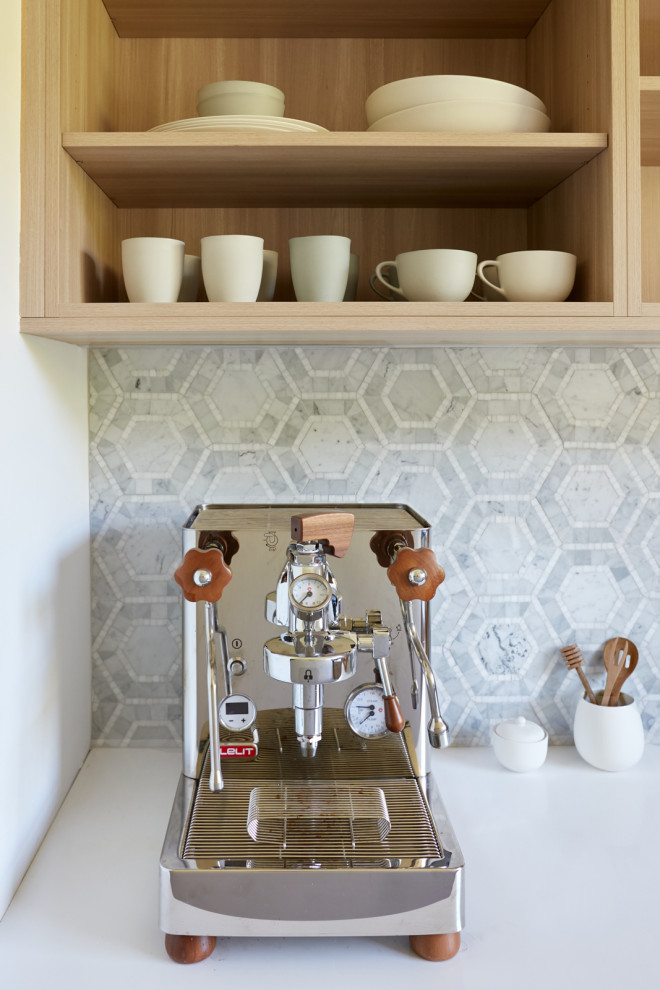Design ideas for a mid-sized contemporary open plan kitchen in Sydney with a single-bowl sink, shaker cabinets, white cabinets, marble benchtops, white splashback, marble splashback, black appliances, light hardwood floors, with island, brown floor and white benchtop.
