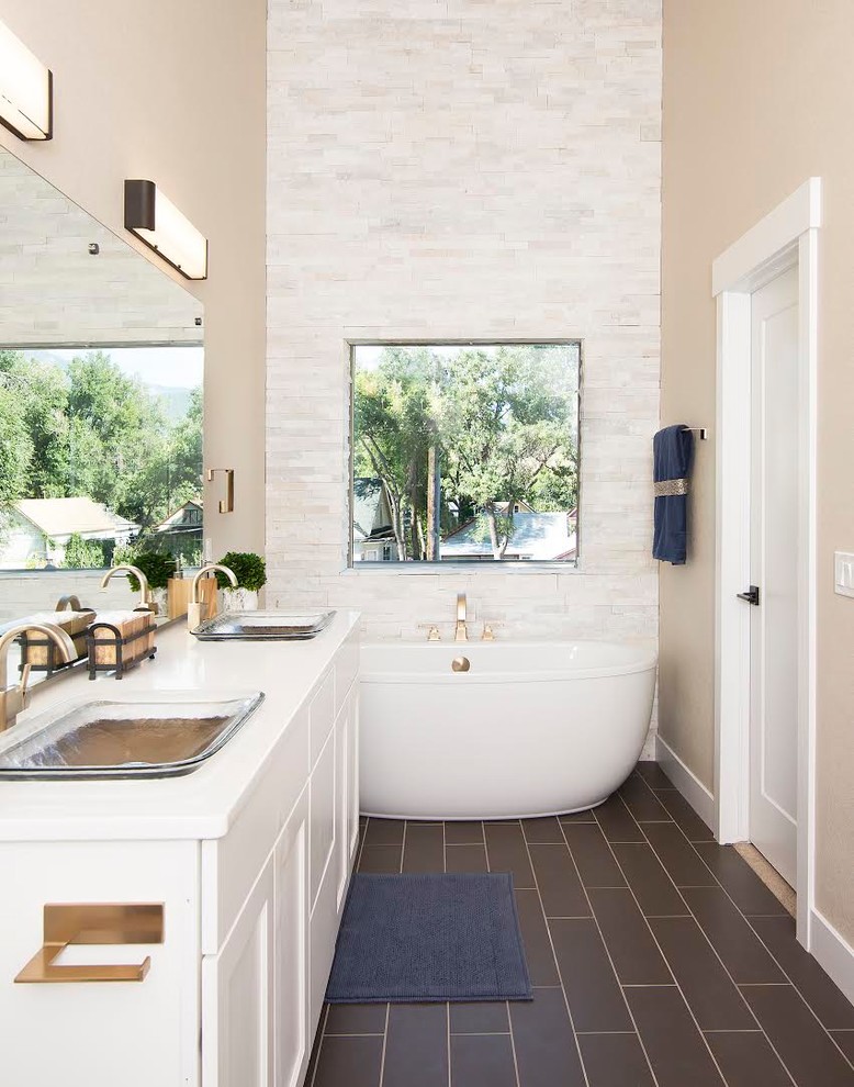This is an example of a mid-sized transitional master bathroom in Denver with recessed-panel cabinets, white cabinets, a freestanding tub, an alcove shower, beige tile, white tile, matchstick tile, beige walls, porcelain floors, a drop-in sink, engineered quartz benchtops and black floor.