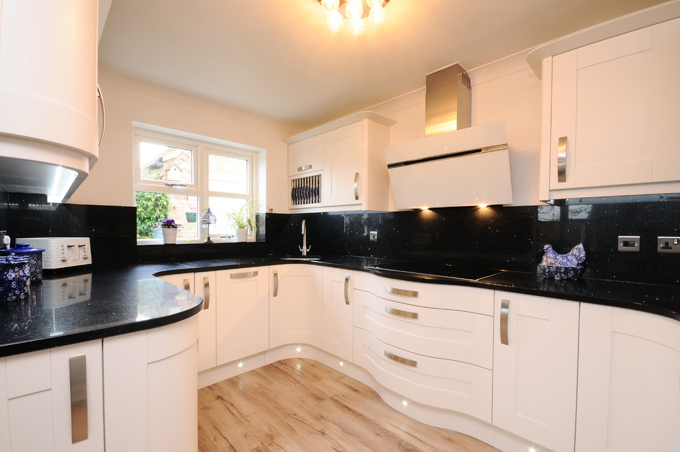 Small contemporary u-shaped eat-in kitchen in Other with an integrated sink, shaker cabinets, white cabinets, solid surface benchtops, black splashback, stainless steel appliances, linoleum floors and no island.