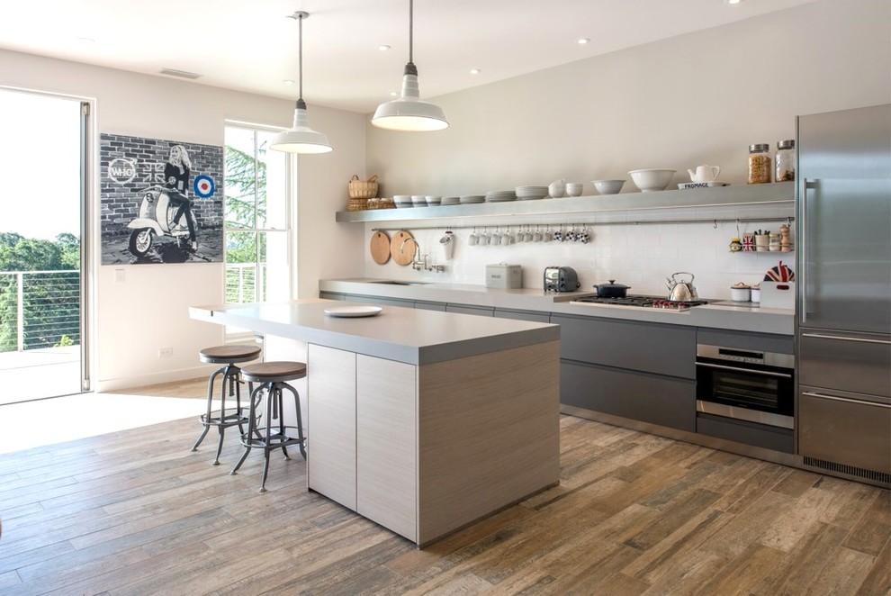 This is an example of a small contemporary galley eat-in kitchen in Other with a single-bowl sink, flat-panel cabinets, light wood cabinets, quartz benchtops, white splashback, ceramic splashback, stainless steel appliances, medium hardwood floors, with island, brown floor and grey benchtop.
