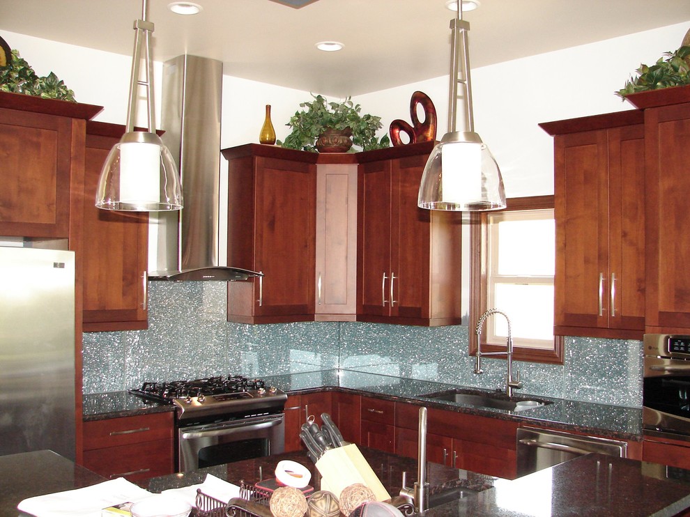 Example of a transitional kitchen design in Omaha with an undermount sink, medium tone wood cabinets, granite countertops, blue backsplash, glass tile backsplash and stainless steel appliances