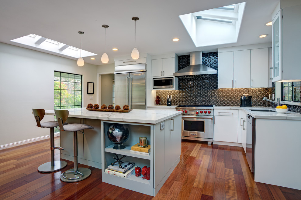 This is an example of a mid-sized contemporary l-shaped open plan kitchen in San Francisco with an undermount sink, flat-panel cabinets, white cabinets, quartz benchtops, grey splashback, ceramic splashback, stainless steel appliances, medium hardwood floors, with island and red floor.