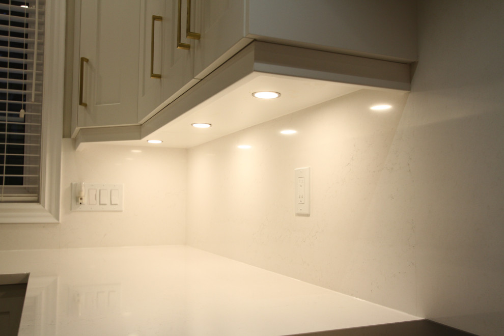 Immagine di una grande cucina design con lavello sottopiano, ante con riquadro incassato, ante bianche, top in quarzo composito, paraspruzzi bianco, paraspruzzi in quarzo composito, elettrodomestici in acciaio inossidabile, pavimento in gres porcellanato, pavimento grigio e top bianco