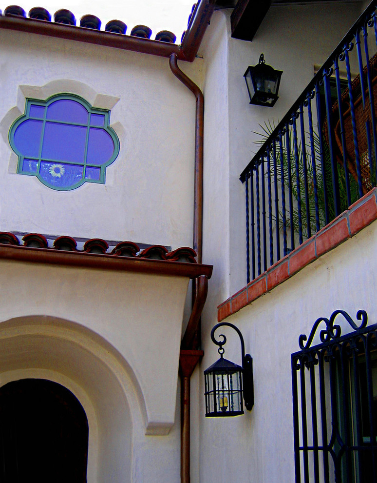 This is an example of a mid-sized mediterranean two-storey stucco white house exterior in Santa Barbara with a hip roof and a tile roof.
