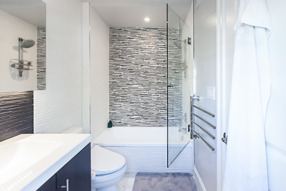 Small modern master bathroom in DC Metro with an integrated sink, flat-panel cabinets, dark wood cabinets, solid surface benchtops, a drop-in tub, an alcove shower, a bidet, white tile, ceramic tile, grey walls and marble floors.