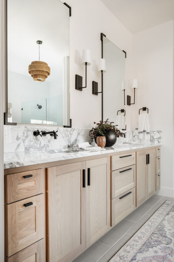This is an example of a large transitional master bathroom in Oklahoma City with shaker cabinets, light wood cabinets, a freestanding tub, a double shower, a one-piece toilet, white tile, porcelain tile, white walls, porcelain floors, a wall-mount sink, marble benchtops, grey floor, a hinged shower door, white benchtops, a shower seat, a double vanity and a built-in vanity.