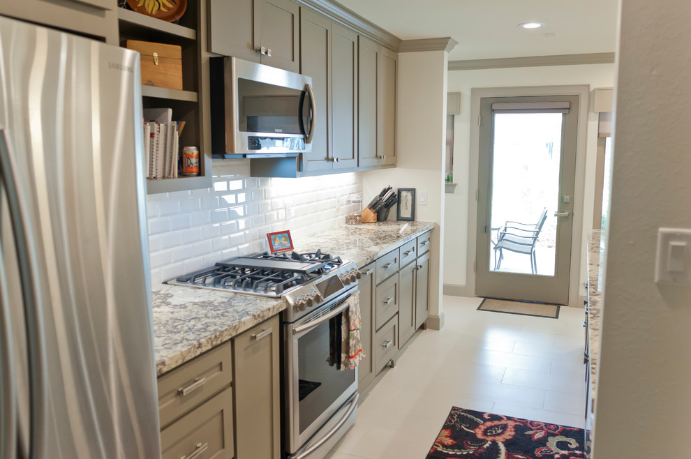 Mid-sized transitional galley kitchen in Houston with an undermount sink, shaker cabinets, grey cabinets, granite benchtops, white splashback, subway tile splashback, stainless steel appliances, porcelain floors and a peninsula.