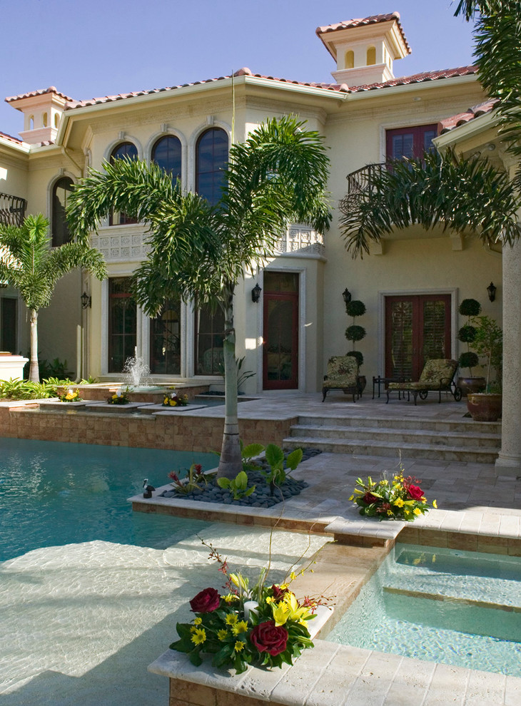 Mid-sized mediterranean backyard custom-shaped lap pool in Miami with a hot tub and tile.