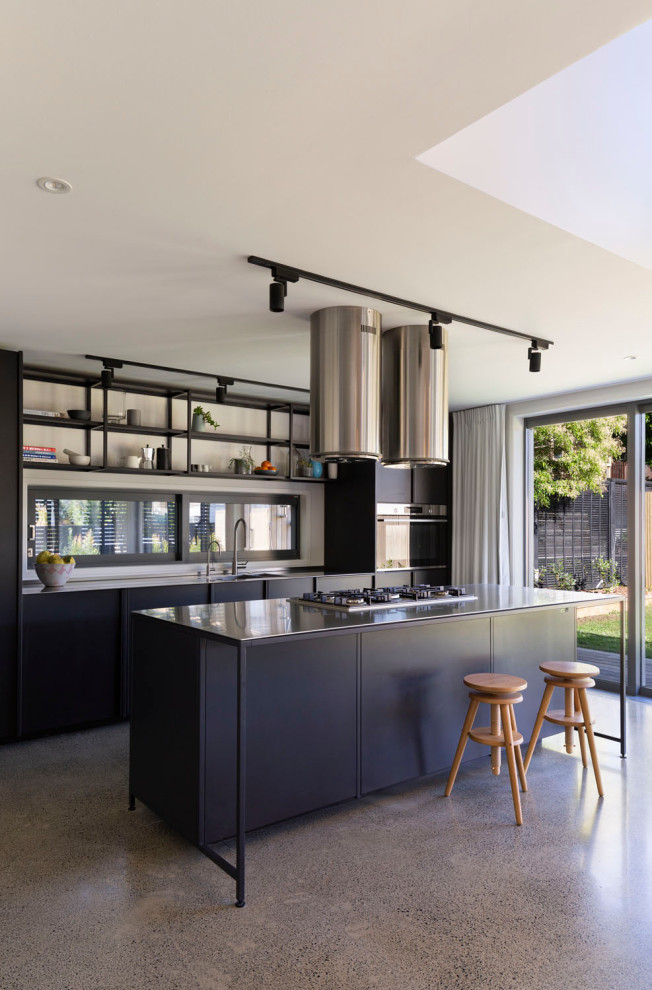 Foto på ett mellanstort funkis grå linjärt kök och matrum, med en nedsänkt diskho, luckor med infälld panel, svarta skåp, bänkskiva i rostfritt stål, vitt stänkskydd, rostfria vitvaror, betonggolv, en köksö och grått golv