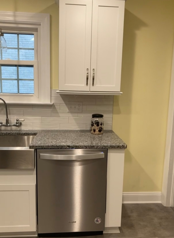 This is an example of a small traditional u-shaped eat-in kitchen in Indianapolis with a double-bowl sink, shaker cabinets, white cabinets, granite benchtops, white splashback, subway tile splashback, stainless steel appliances, vinyl floors, no island, brown floor and multi-coloured benchtop.