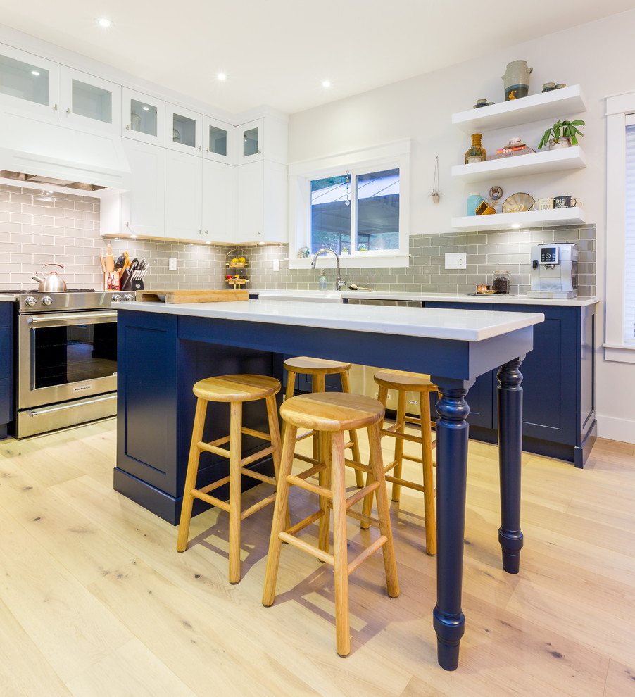 Inspiration for a large transitional u-shaped light wood floor open concept kitchen remodel with a farmhouse sink, shaker cabinets, blue cabinets, quartz countertops, gray backsplash, glass tile backsplash, stainless steel appliances, an island and white countertops