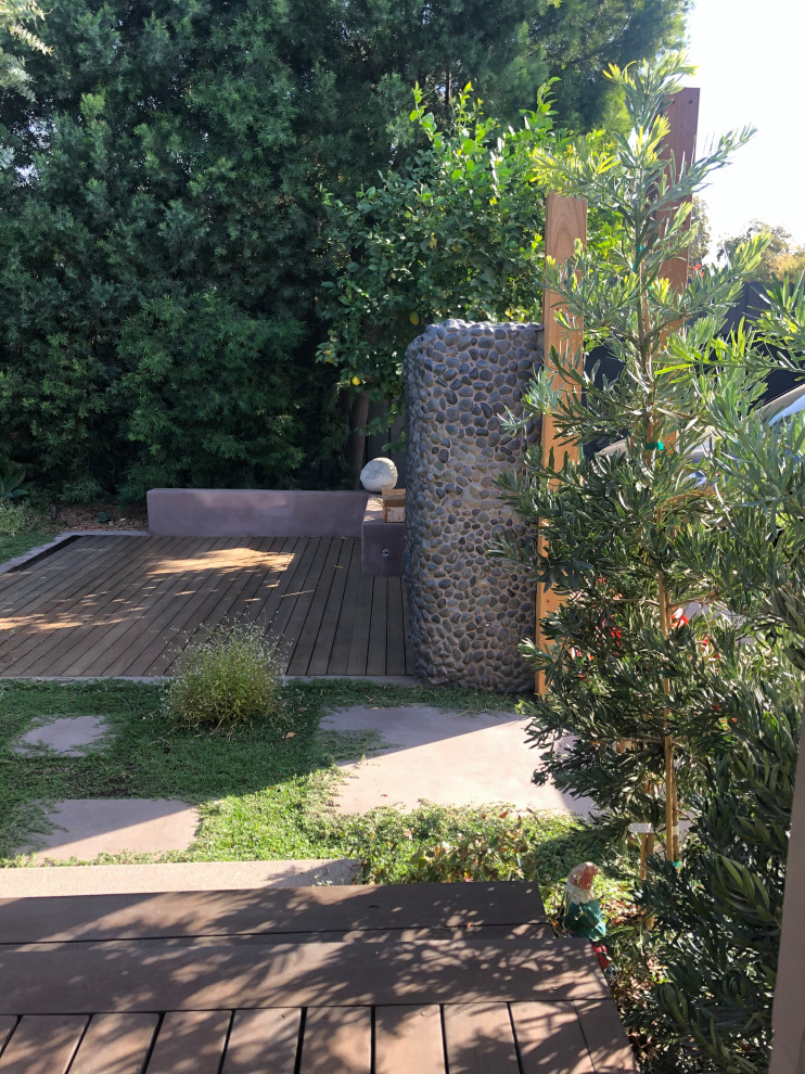 Пример оригинального дизайна: солнечный, весенний засухоустойчивый сад среднего размера на заднем дворе в стиле фьюжн с перегородкой для приватности, хорошей освещенностью, настилом и с деревянным забором