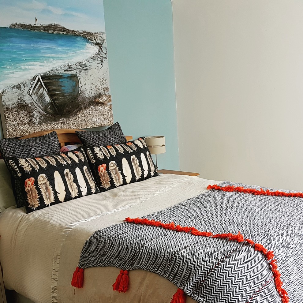 This is an example of a mid-sized beach style master bedroom in Cornwall with blue walls, carpet and grey floor.
