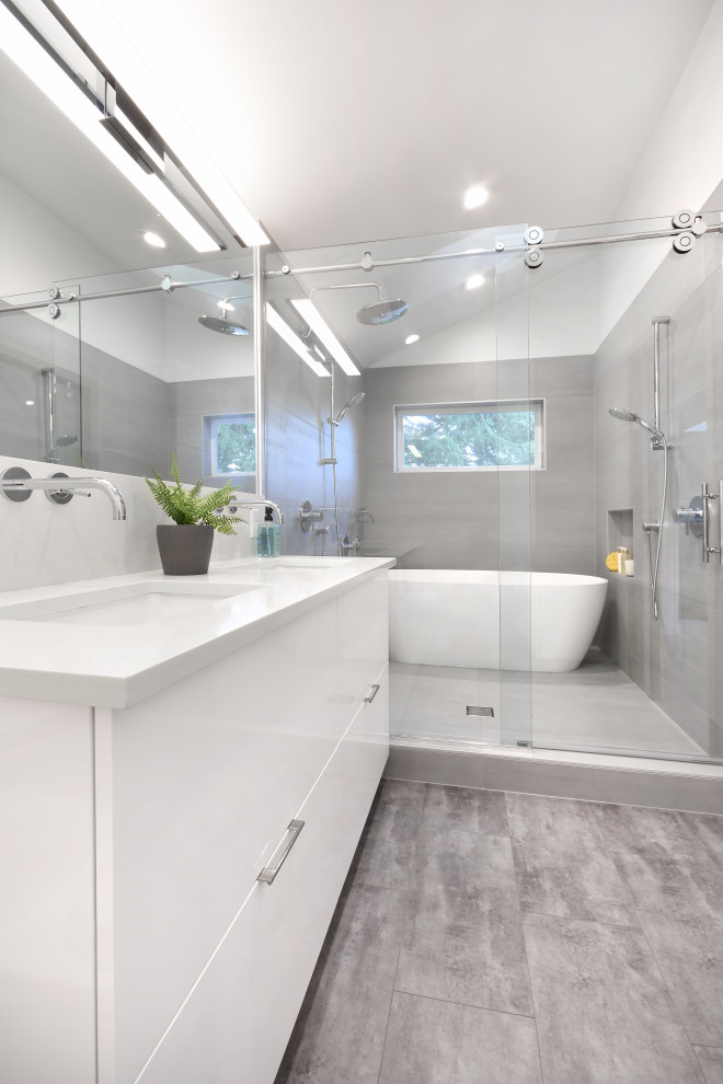 This is an example of a medium sized contemporary ensuite wet room bathroom in Seattle with flat-panel cabinets, white cabinets, a freestanding bath, a one-piece toilet, grey tiles, porcelain tiles, white walls, vinyl flooring, a submerged sink, engineered stone worktops, brown floors, a sliding door, white worktops, a shower bench, double sinks and a built in vanity unit.