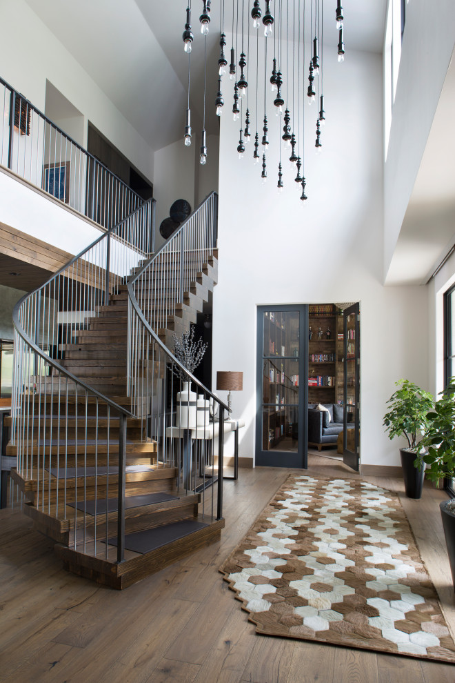 This is an example of a large contemporary wood curved staircase in Denver with wood risers and metal railing.