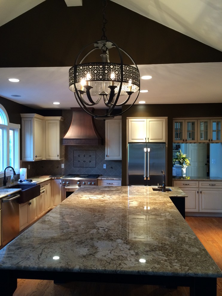 Inspiration for a transitional l-shaped medium tone wood floor kitchen remodel in St Louis with a farmhouse sink, raised-panel cabinets, granite countertops and an island