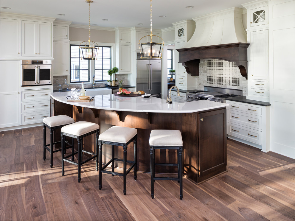 Photo of a traditional kitchen in Minneapolis with a farmhouse sink, shaker cabinets, white cabinets, multi-coloured splashback, stainless steel appliances, light hardwood floors and with island.