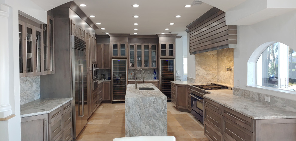 This is an example of a large modern u-shaped eat-in kitchen in Tampa with an undermount sink, shaker cabinets, grey cabinets, quartz benchtops, brown splashback, engineered quartz splashback, stainless steel appliances, limestone floors, with island, beige floor and brown benchtop.