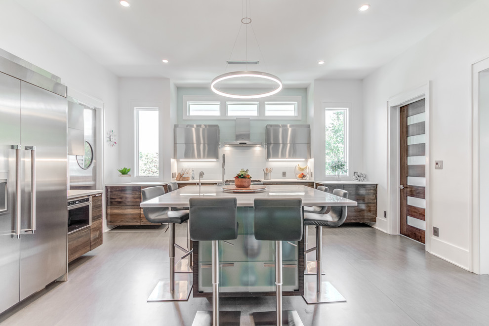 This is an example of an expansive contemporary l-shaped kitchen in Wilmington with an integrated sink, white splashback, glass tile splashback, porcelain floors, grey floor, white benchtop, flat-panel cabinets, dark wood cabinets and with island.