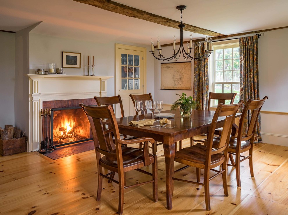 Photo of a country separate dining room in Boston with light hardwood floors, a standard fireplace and a wood fireplace surround.