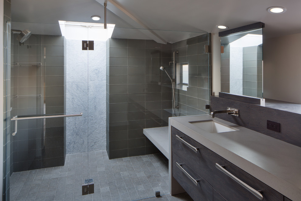 This is an example of a mid-sized contemporary master bathroom in San Francisco with an undermount sink, flat-panel cabinets, dark wood cabinets, granite benchtops, a curbless shower, gray tile, glass tile, beige walls and porcelain floors.