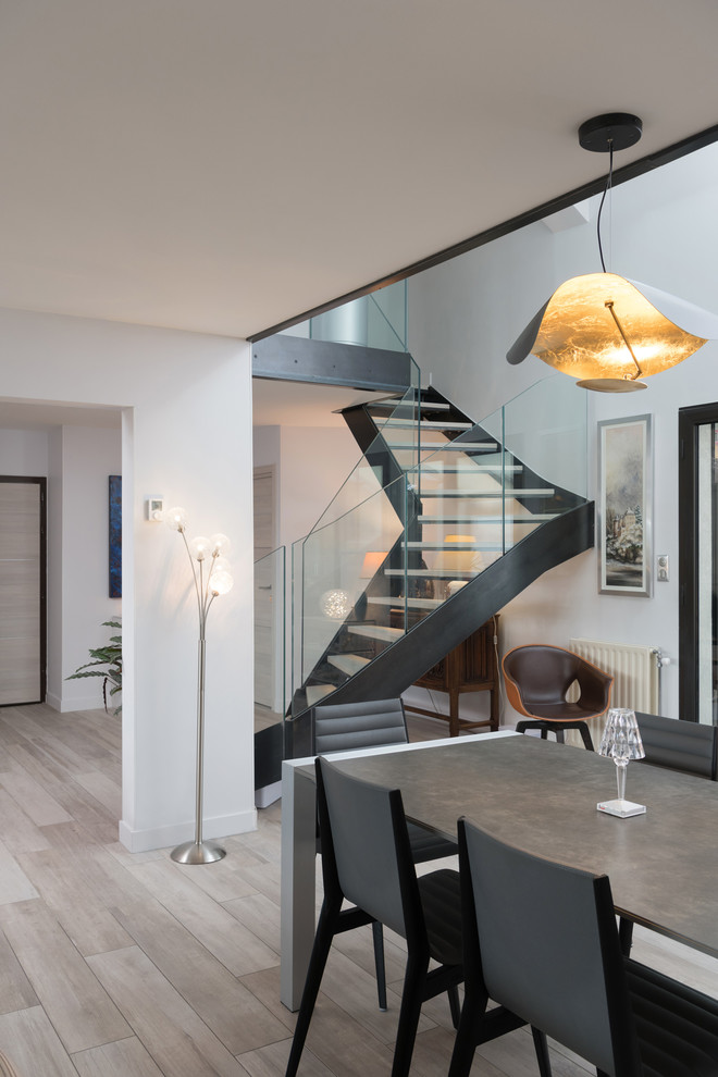 Photo of a contemporary wood spiral staircase in Lyon with metal risers and glass railing.
