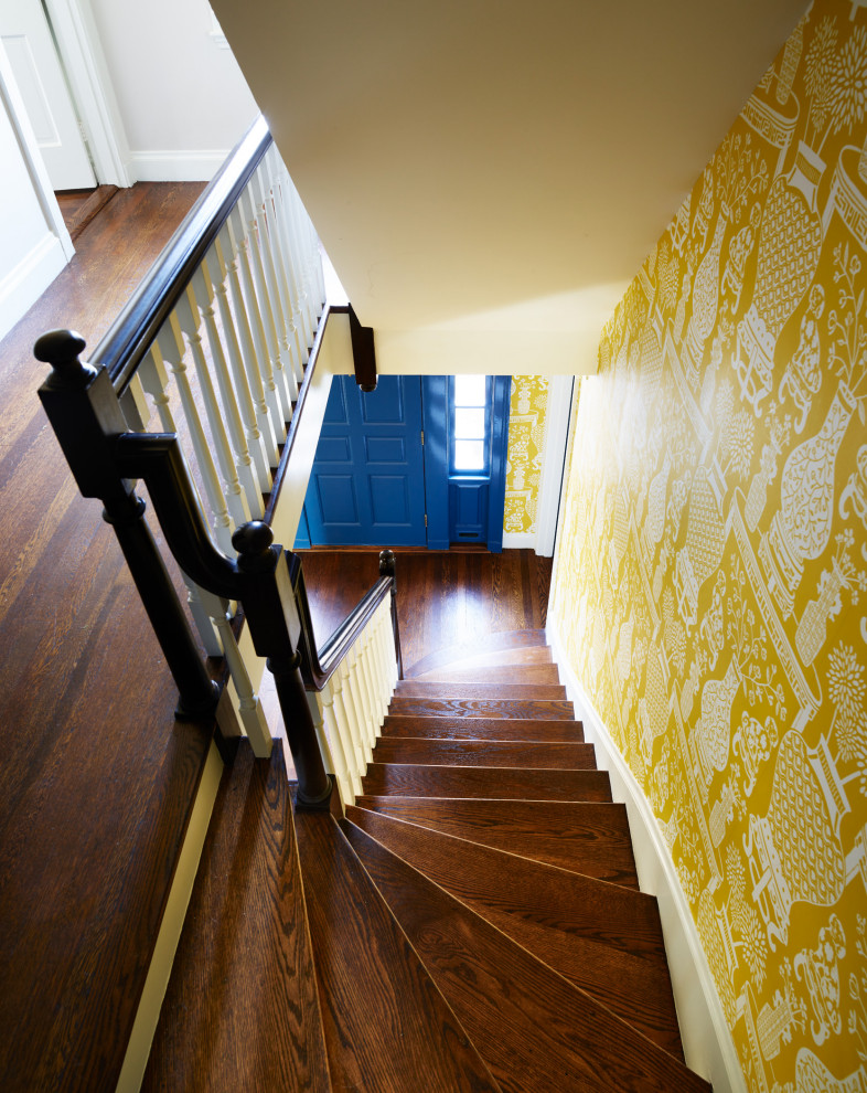 Cette image montre une grande entrée traditionnelle avec un couloir, un mur jaune, un sol en bois brun, une porte simple, une porte bleue, un sol marron et du papier peint.