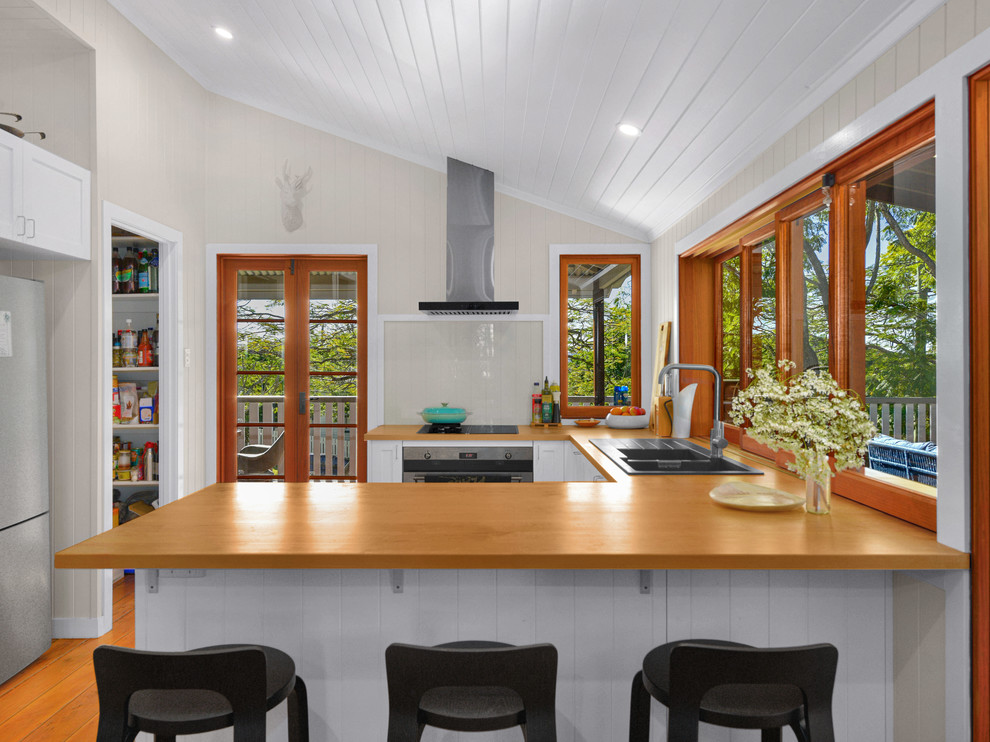 Design ideas for a country u-shaped kitchen in Brisbane with a double-bowl sink, wood benchtops, glass sheet splashback, stainless steel appliances and a peninsula.