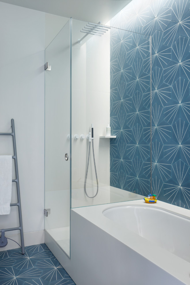 This is an example of a contemporary bathroom in London with a drop-in tub, a corner shower, blue tile, white tile, ceramic tile, white walls, ceramic floors, blue floor and a hinged shower door.