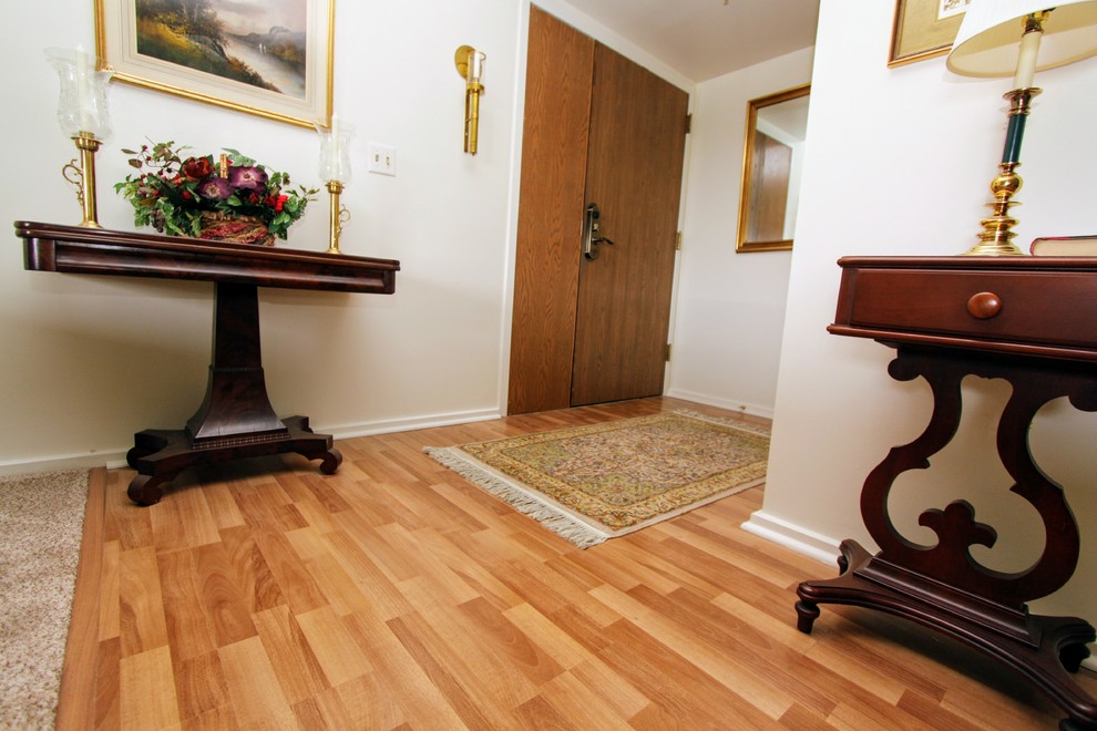 Example of a mid-sized transitional light wood floor foyer design with white walls and a dark wood front door