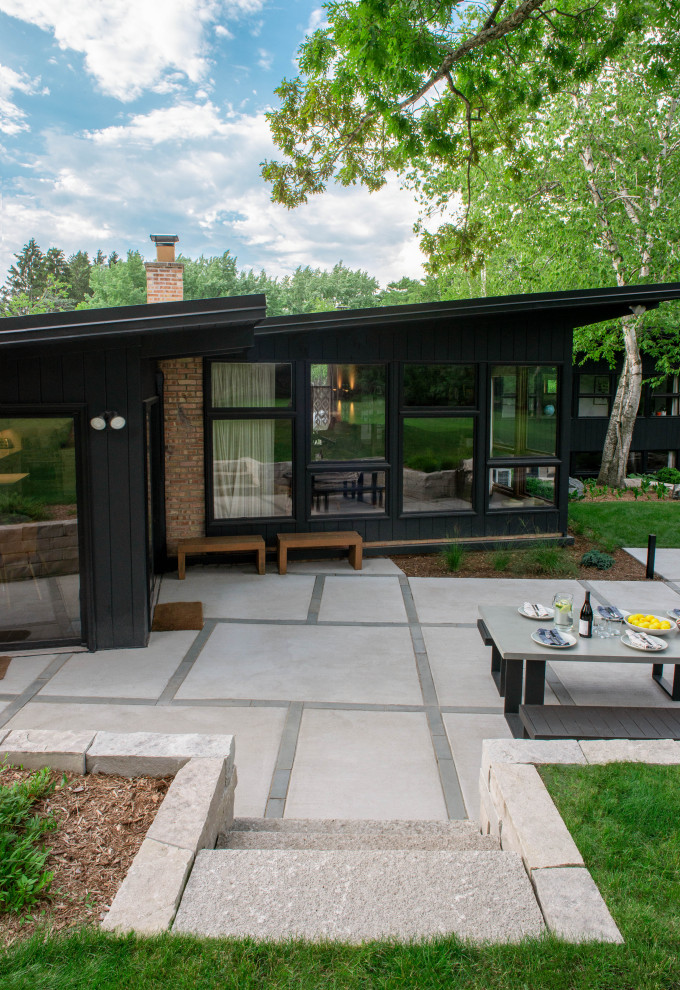 Immagine di un patio o portico moderno di medie dimensioni e dietro casa con lastre di cemento