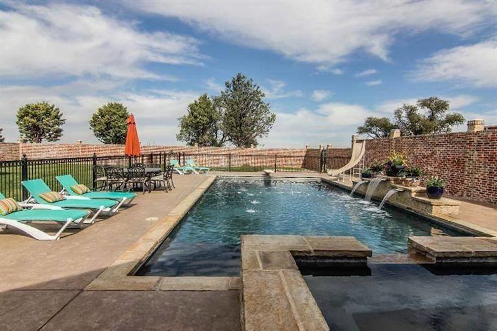 This is an example of a mid-sized traditional backyard rectangular lap pool in Austin with a water slide and stamped concrete.