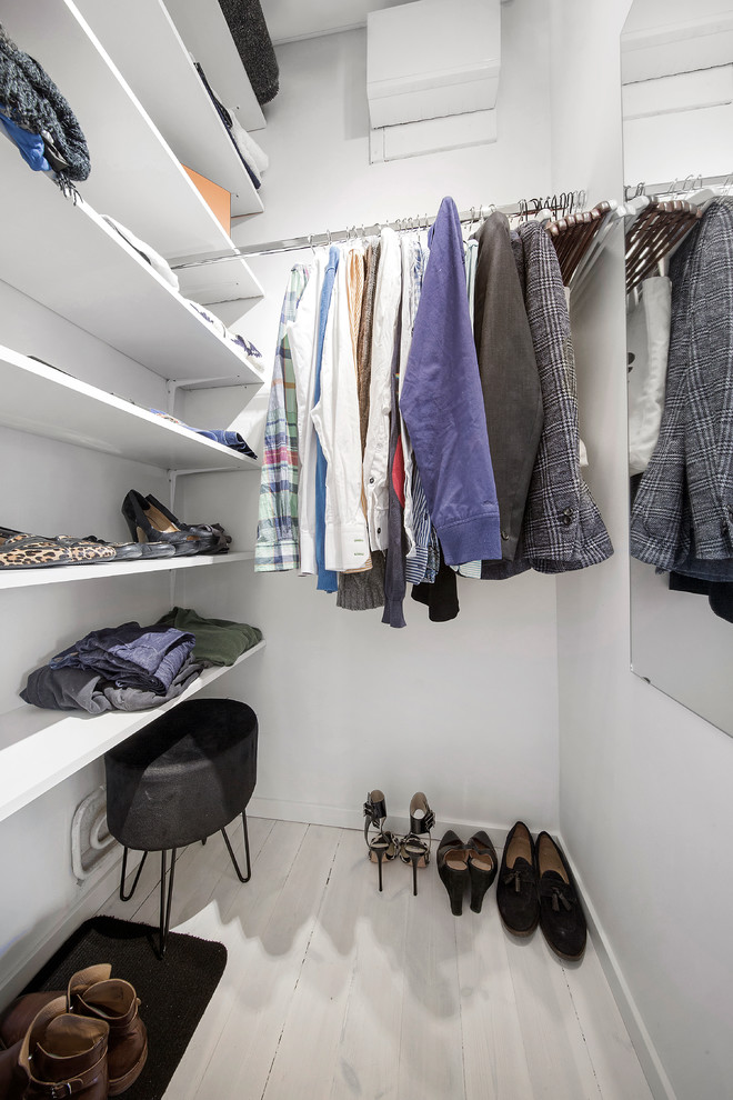 Photo of a scandinavian gender-neutral walk-in wardrobe in Stockholm with open cabinets, white cabinets, light hardwood floors and beige floor.