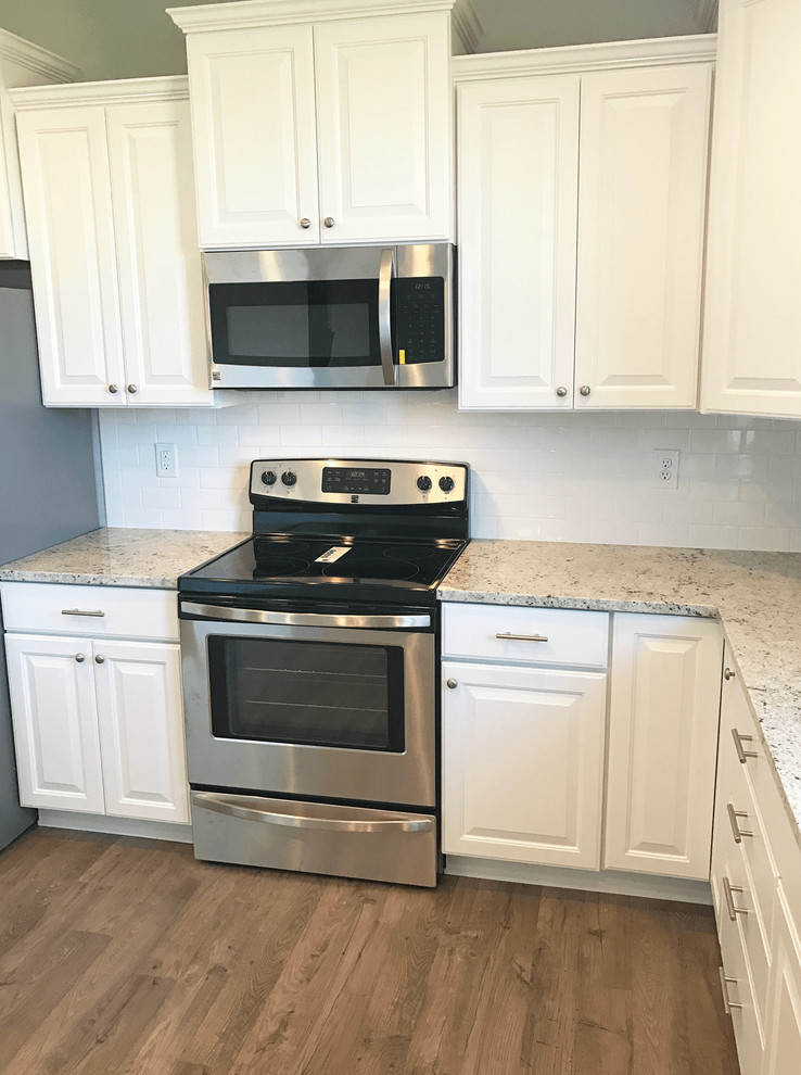 Inspiration for a mid-sized u-shaped eat-in kitchen in Indianapolis with a drop-in sink, white cabinets, tile benchtops, white splashback, stainless steel appliances, laminate floors and grey floor.