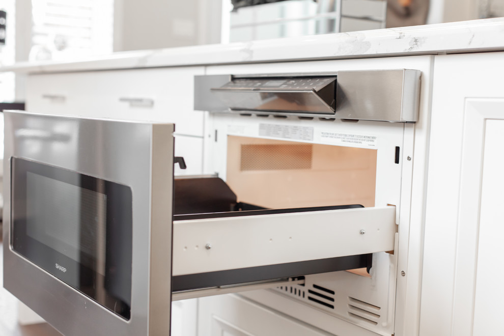 Enclosed kitchen - large transitional l-shaped medium tone wood floor and brown floor enclosed kitchen idea with an undermount sink, recessed-panel cabinets, white cabinets, quartz countertops, gray backsplash, ceramic backsplash, stainless steel appliances, an island and white countertops