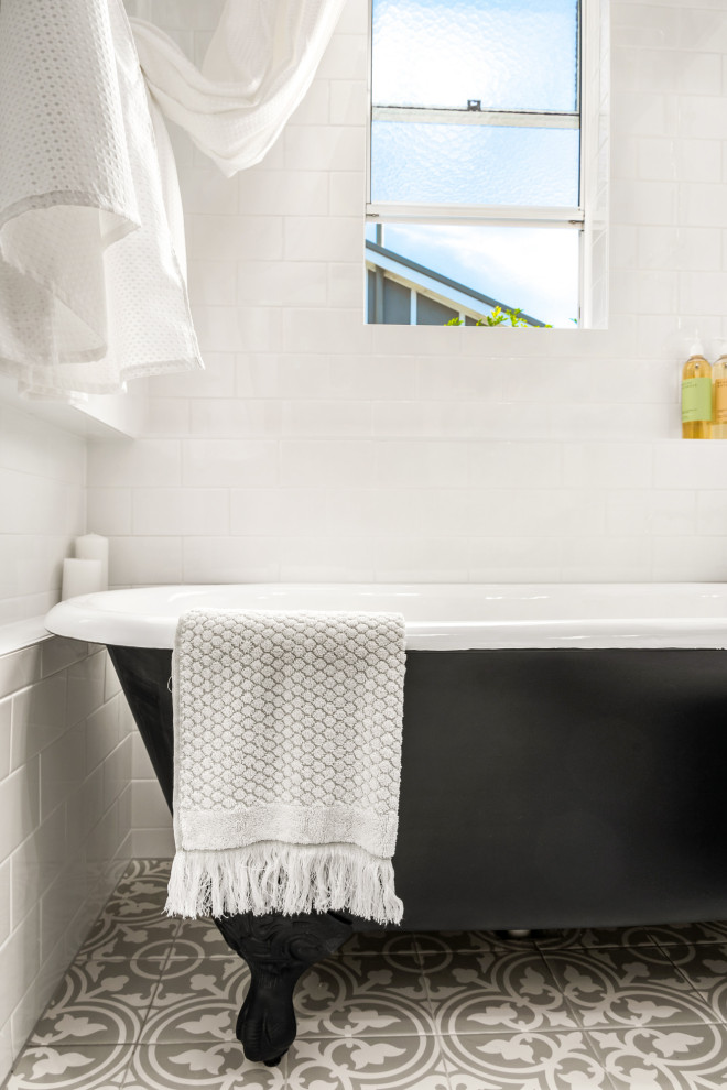 Photo of a small traditional master bathroom in Newcastle - Maitland with furniture-like cabinets, black cabinets, a claw-foot tub, a shower/bathtub combo, a two-piece toilet, white tile, a vessel sink, grey floor, a shower curtain, white benchtops, a single vanity and a freestanding vanity.