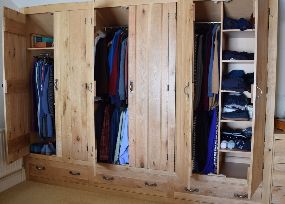 This is an example of a large traditional storage and wardrobe in Buckinghamshire with beaded inset cabinets, medium wood cabinets, carpet, beige floor and exposed beam.