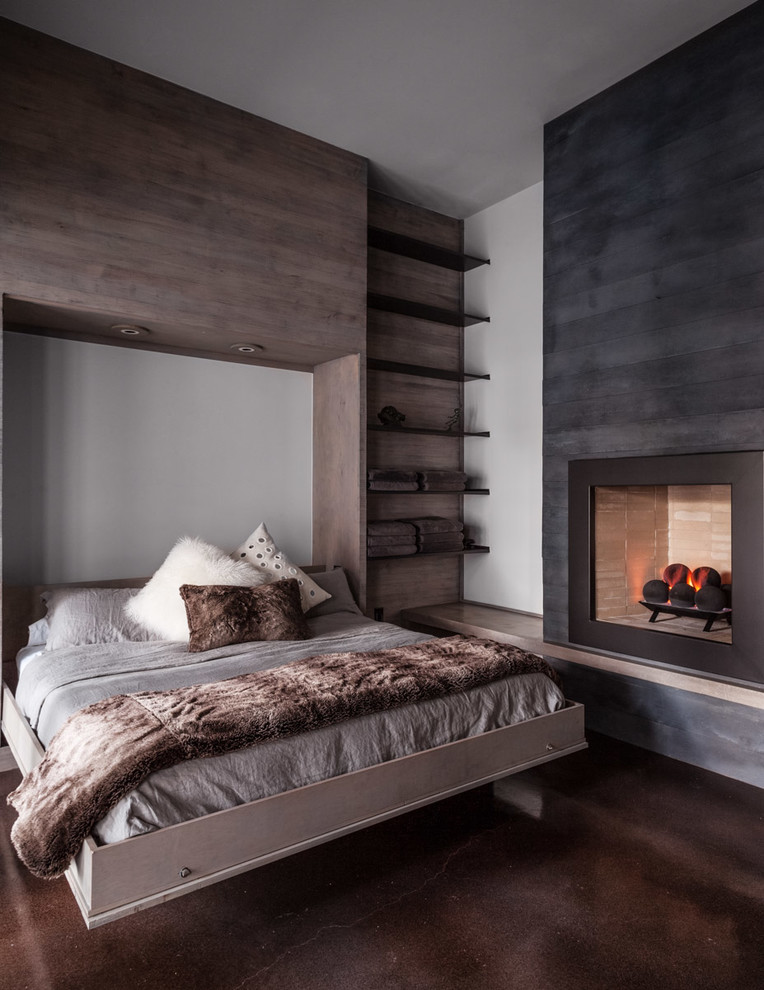 This is an example of a contemporary bedroom in Dallas with white walls, a standard fireplace and brown floor.