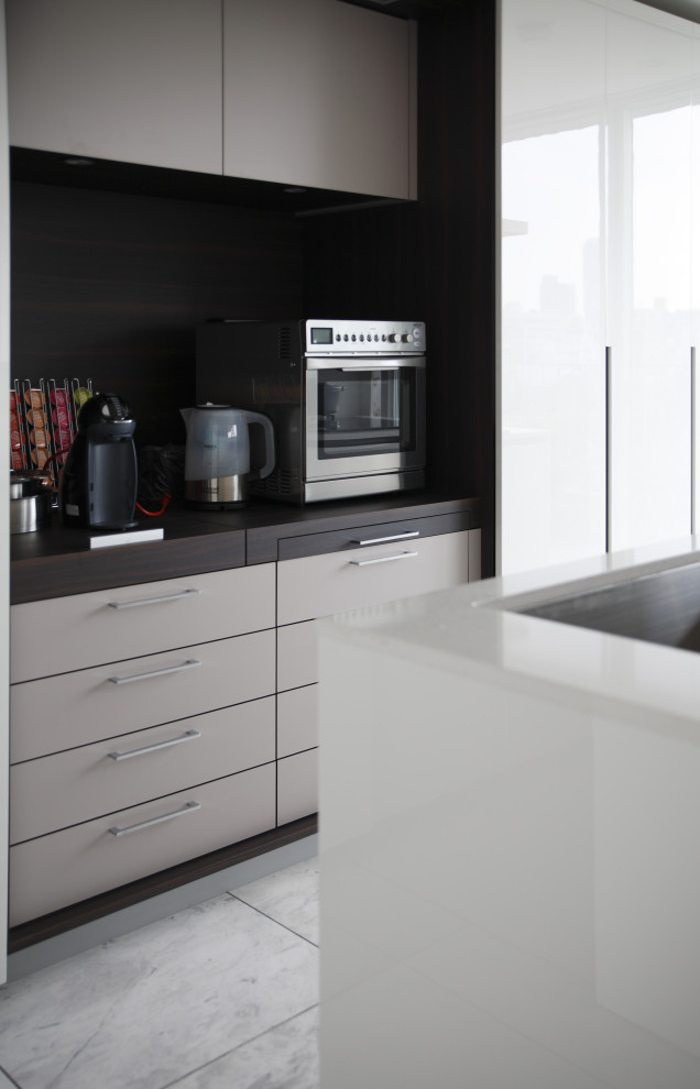 Modelo de cocina lineal moderna abierta con fregadero bajoencimera, armarios con paneles lisos, puertas de armario blancas, encimera de cuarzo compacto, una isla y encimeras blancas