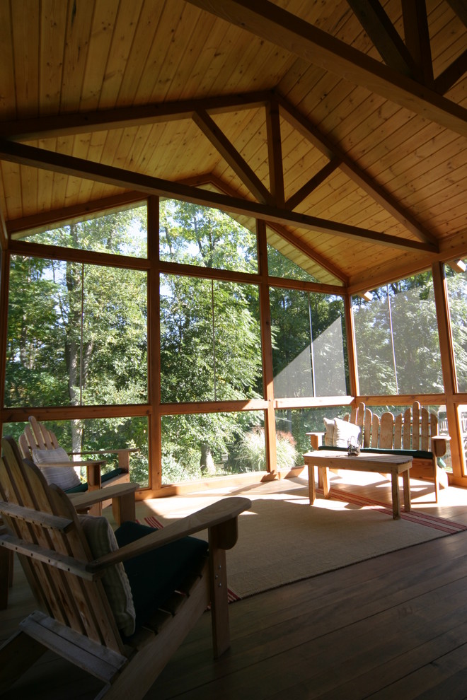 This is an example of a large traditional screened-in back porch design in Detroit with decking and a roof extension.