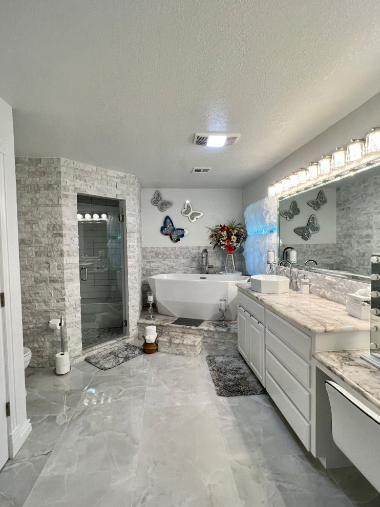 This is an example of a mid-sized modern master bathroom in Other with flat-panel cabinets, white cabinets, a freestanding tub, a corner shower, a one-piece toilet, gray tile, stone tile, white walls, porcelain floors, granite benchtops, grey floor, a hinged shower door, grey benchtops, a shower seat, a single vanity and a built-in vanity.