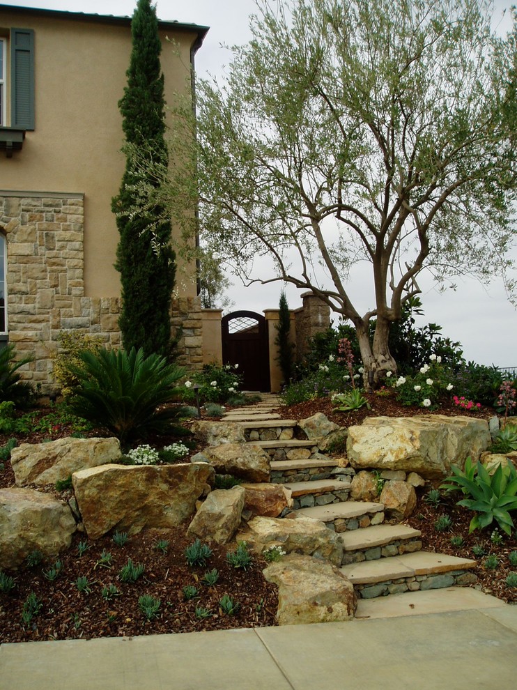 Design ideas for a mediterranean sloped garden in San Diego with natural stone pavers.