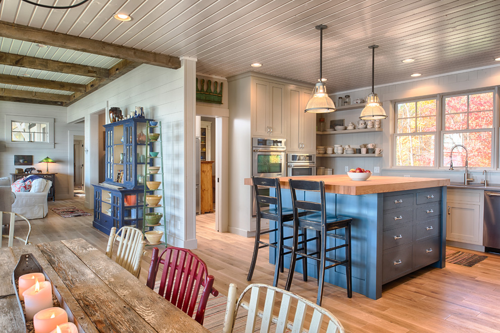 Inspiration for a mid-sized beach style l-shaped eat-in kitchen in Minneapolis with shaker cabinets, grey cabinets, quartz benchtops, white splashback, stainless steel appliances, light hardwood floors and with island.