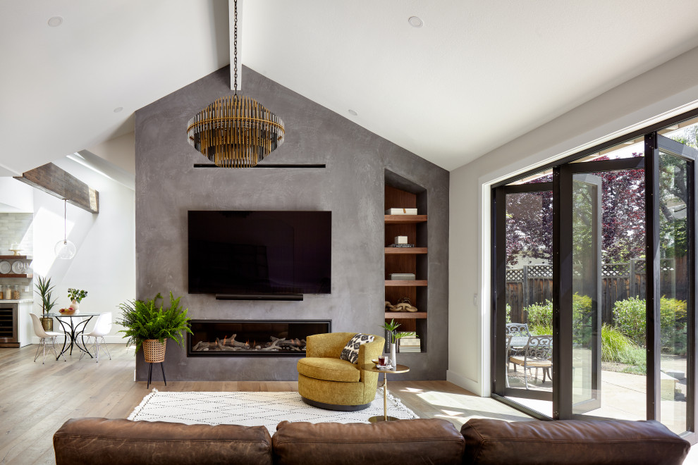 Photo of a large formal open concept living room in San Francisco with beige walls, light hardwood floors, a ribbon fireplace, a plaster fireplace surround, a wall-mounted tv, brown floor and vaulted.
