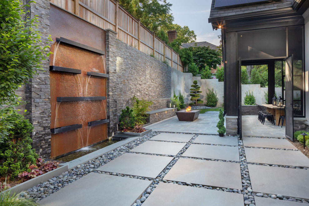 Contemporary backyard partial sun formal garden in DC Metro with with waterfall and natural stone pavers for summer.