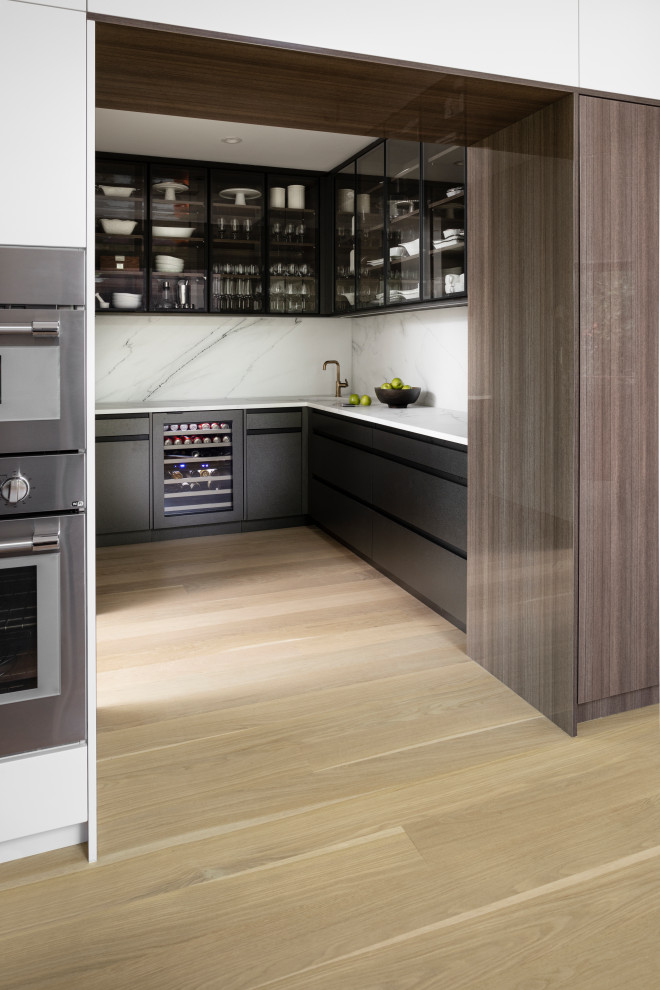Design ideas for an u-shaped kitchen pantry in New York with an undermount sink, flat-panel cabinets, brown cabinets, marble benchtops, white splashback, marble splashback, stainless steel appliances, light hardwood floors, with island, beige floor and white benchtop.