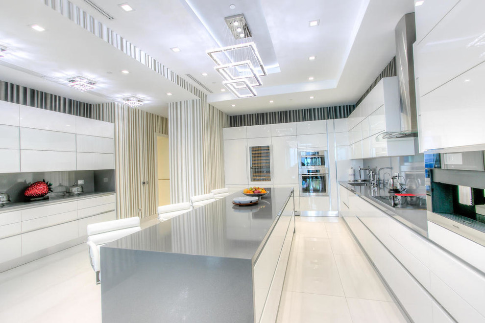 Design ideas for an expansive contemporary l-shaped eat-in kitchen in Miami with an undermount sink, flat-panel cabinets, white cabinets, stainless steel benchtops, metallic splashback, metal splashback, stainless steel appliances, porcelain floors and with island.