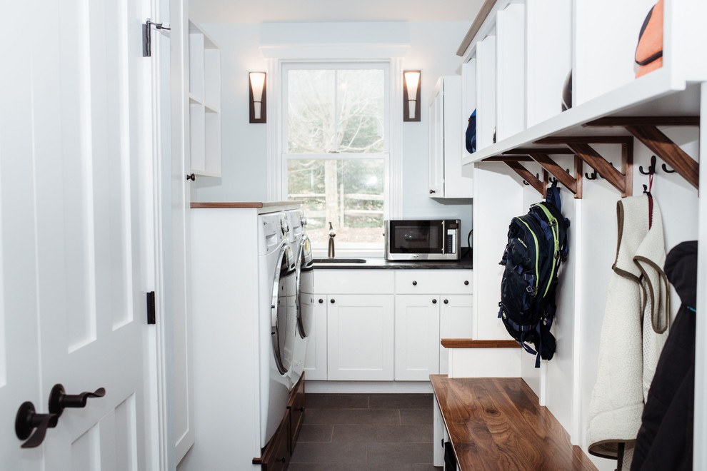 Inspiration for a mid-sized traditional l-shaped utility room in Burlington with an undermount sink, shaker cabinets, white cabinets, soapstone benchtops, blue walls, porcelain floors, a side-by-side washer and dryer, brown floor and black benchtop.